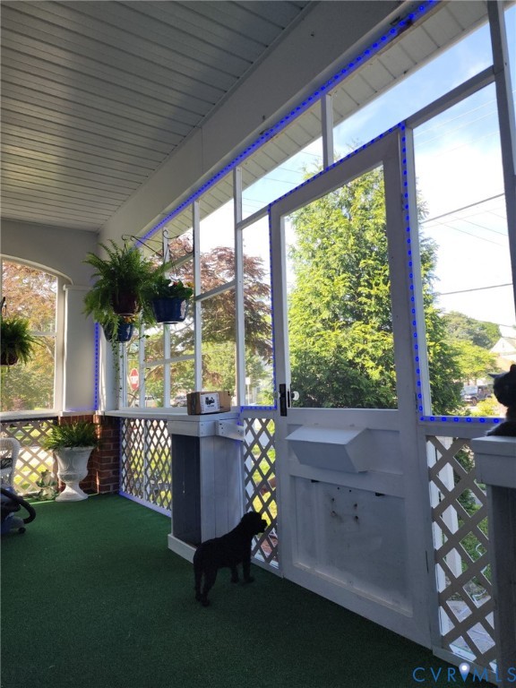 Enclosed porch featuring white lattice railings, full-height window screening, a solid door with a built-in pet portal, and a tongue-and-groove ceiling