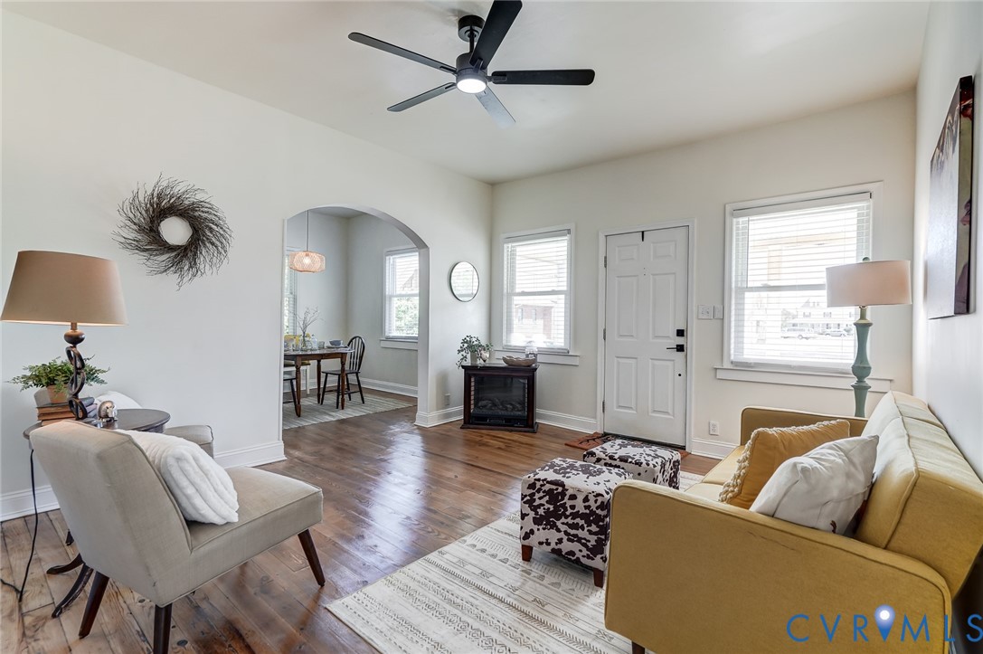 Interior space featuring wood-finish flooring, a matte black ceiling fan, dual windows, and an arched entryway