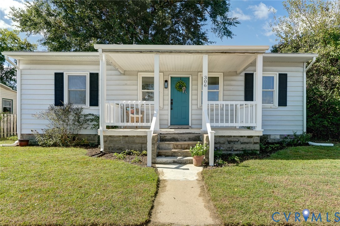 Single-story exterior featuring white horizontal siding, a covered front porch with white railing, and a stone foundation