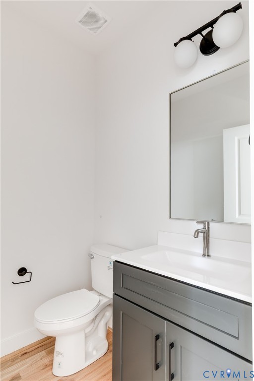 Dark grey vanity with a white countertop, integrated sink, metal hardware, a rectangular wall-mounted mirror, and a three-light fixture with globe shades