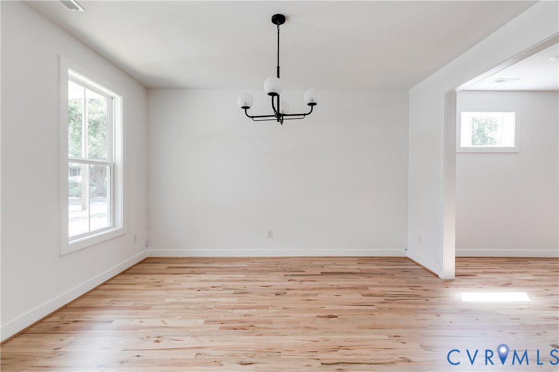Wood-finish flooring, multi-pane window, and matte black chandelier with globe-style glass shades Wood-finish flooring, multi-pane window, and matte black chandelier with globe-style glass shades