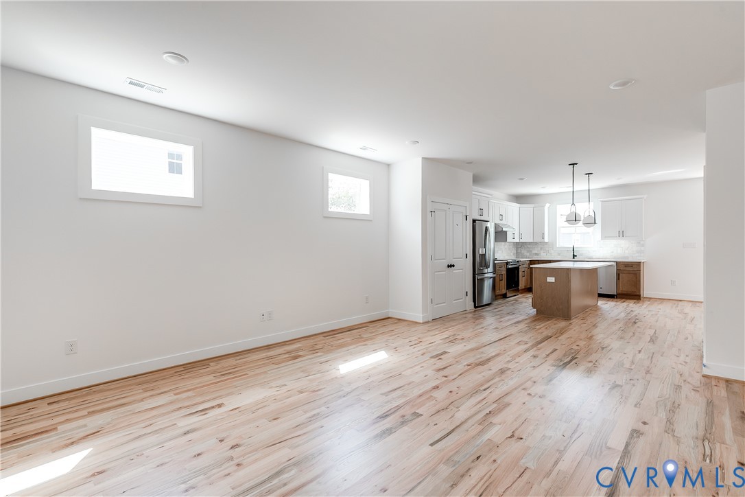 Open-concept area featuring wood-finish flooring, a kitchen island, recessed lighting, and white cabinetry Open-concept area featuring wood-finish flooring, a kitchen island, recessed lighting, and white cabinetry