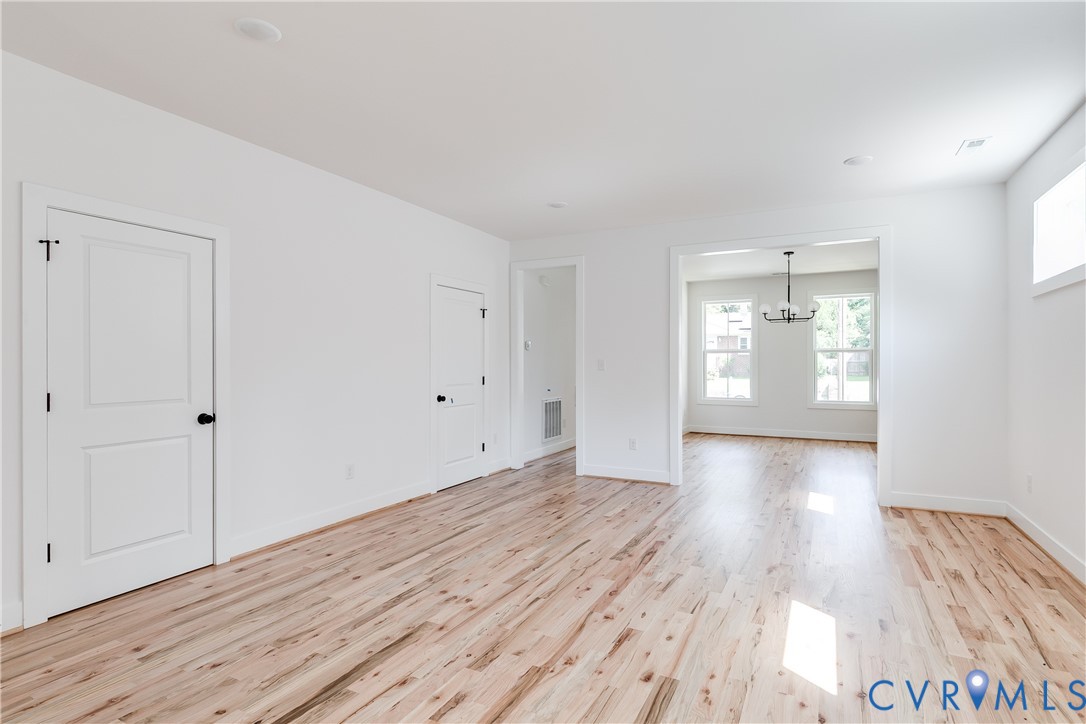 Interior space featuring light wood-finish flooring, recessed lighting, white panel doors, and a multi-light chandelier Interior space featuring light wood-finish flooring, recessed lighting, white panel doors, and a multi-light chandelier