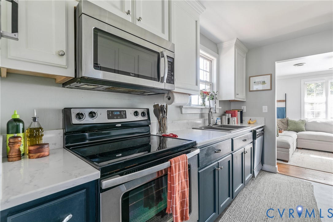Kitchen featuring shaker-style cabinetry, stainless steel appliances, solid-surface countertops, and a double-basin undermount sink