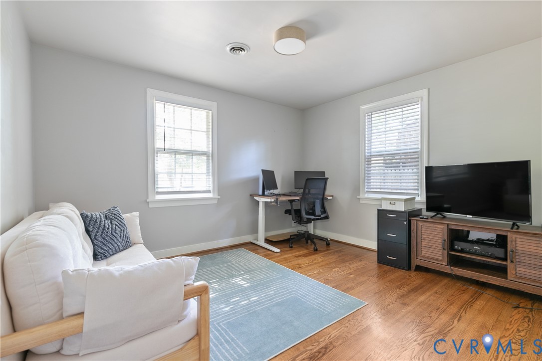 Wood-finish flooring, two multi-pane windows, and a flush-mount drum ceiling light fixture