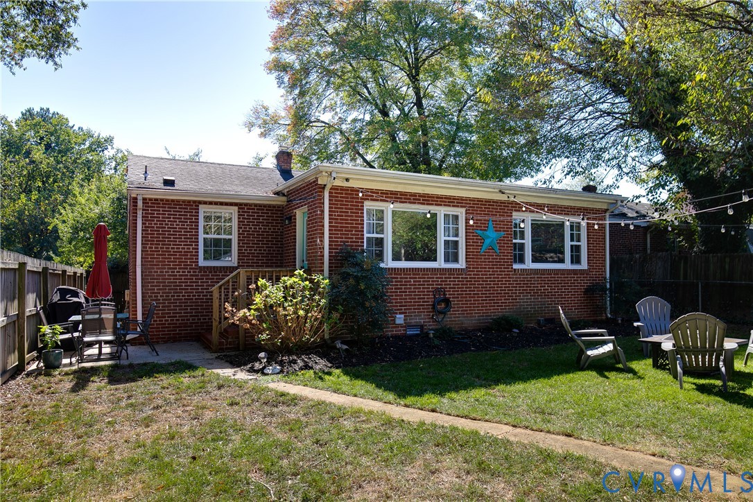 Red brick exterior with white-framed windows, a wood deck, and a fenced backyard