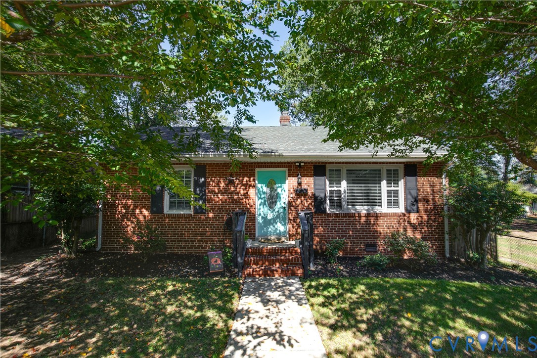 Brick exterior featuring decorative black shutters, a gabled roof, and a central entryway with brick steps