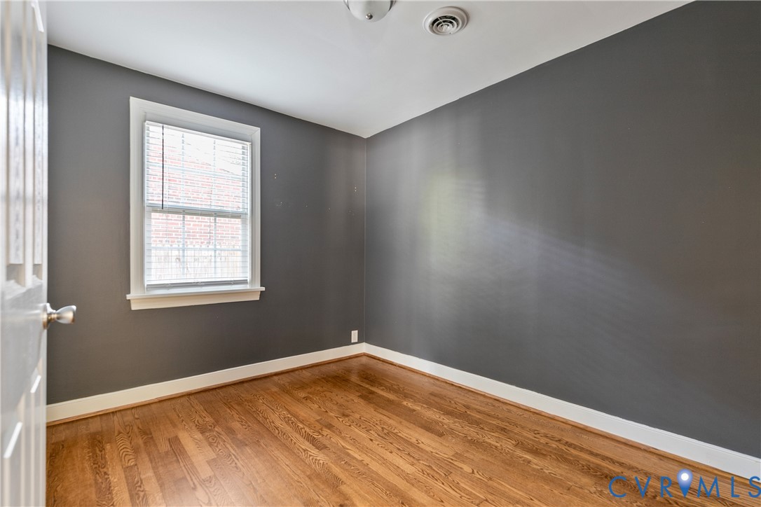 Room featuring dark-toned walls, wood-finish flooring, and a single-hung window with white casing