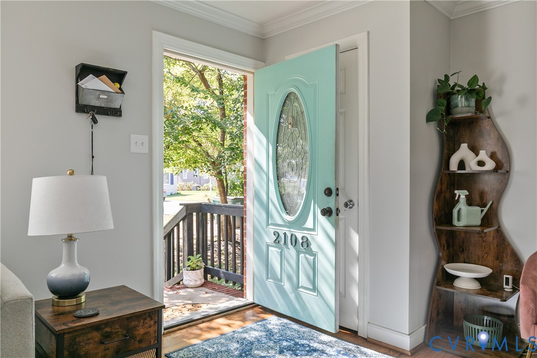 Entryway featuring a painted panel door with an oval glass insert, satin-finish hardware, and wood-finish flooring