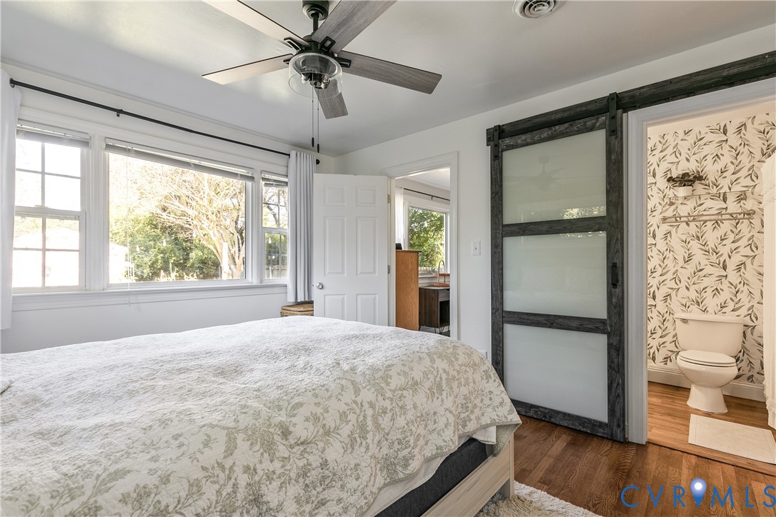 Bedroom featuring wood-finish flooring, a multi-pane window configuration, and a ceiling fan