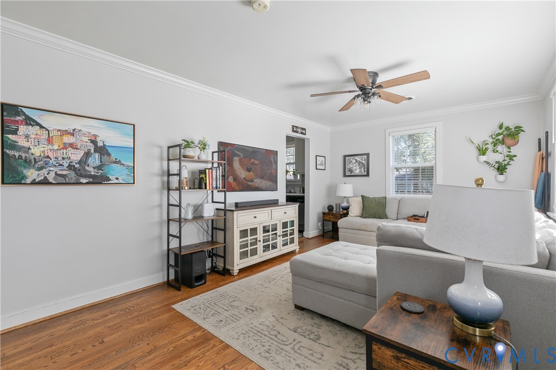 Living area featuring hardwood flooring, crown molding, and a central ceiling fan