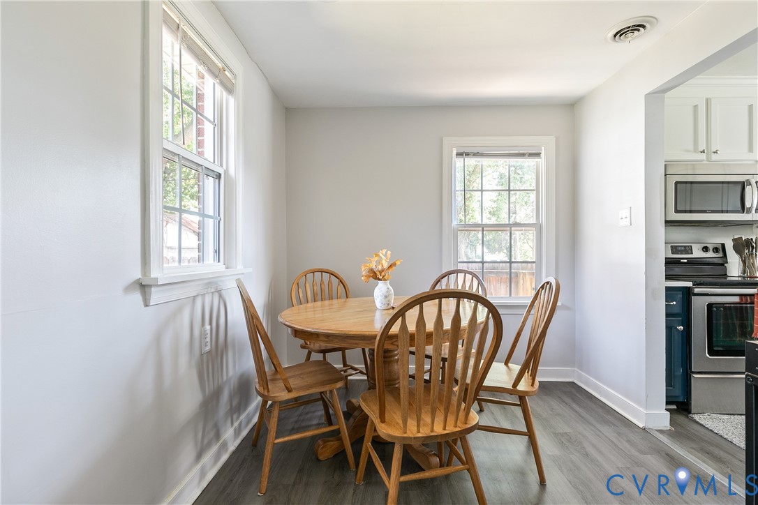 Dining area featuring wood-finish flooring, two large windows with multi-pane glazing, and neutral wall tones