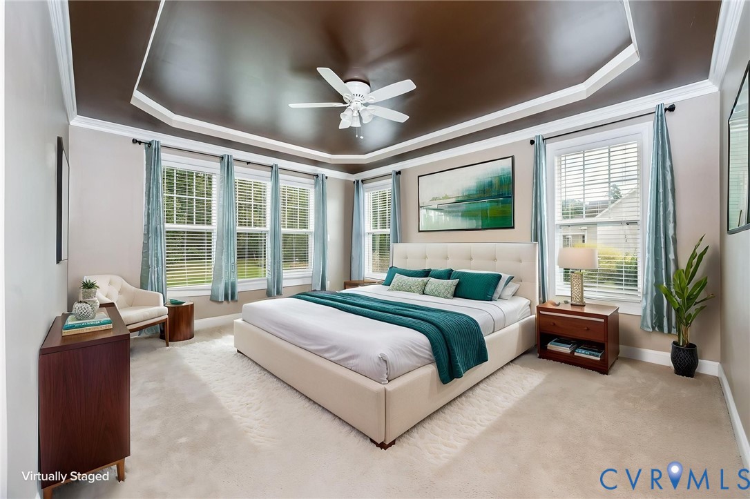 Tray ceiling with crown molding, ceiling fan, and carpeted flooring