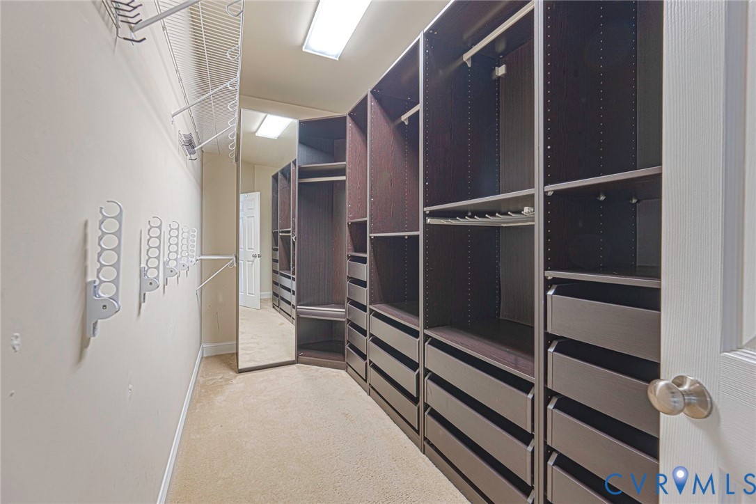 Custom walk-in closet featuring extensive dark-toned built-in cabinetry, integrated drawer storage, full-length mirror, and overhead lighting