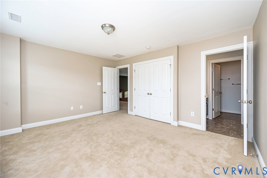 Neutral-toned room featuring neutral wall-to-wall carpeting, double-panel interior doors, a double-door closet, and overhead flush-mount lighting
