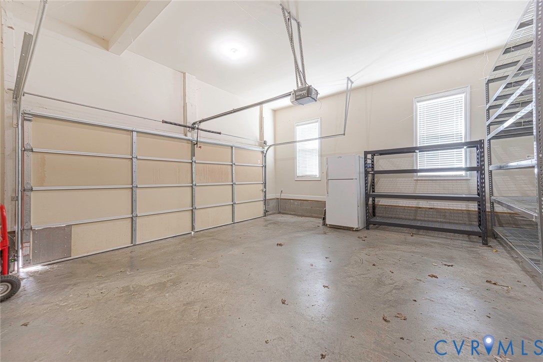 Multi-car garage featuring a concrete floor, high ceilings, automated door opener, and two windows providing natural light