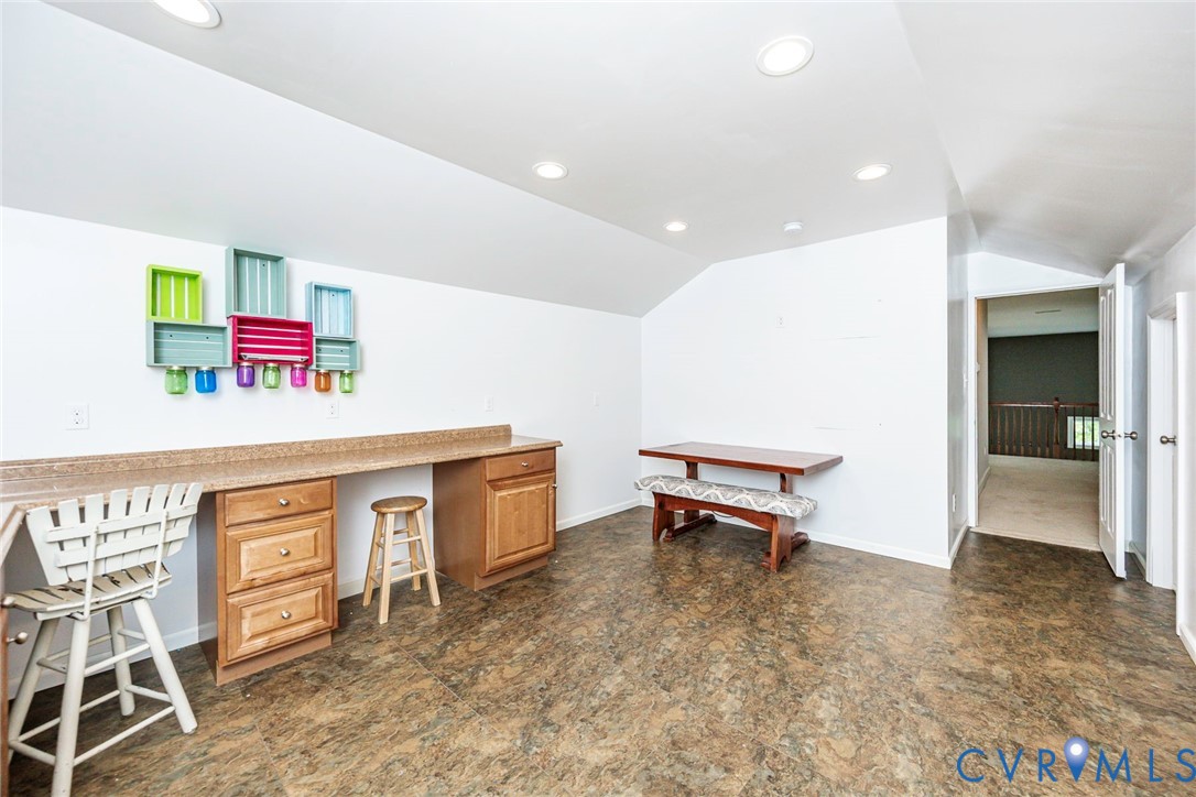 Built-in wood cabinetry with stone-finish countertop, recessed lighting, and resilient flooring