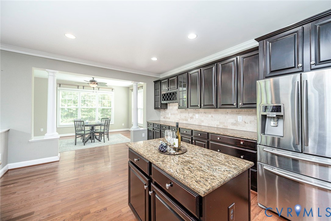 Kitchen featuring dark cabinetry, stone countertops, a center island, stainless steel refrigerator, and recessed lighting