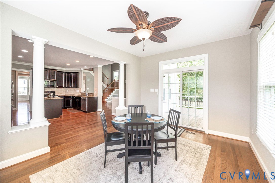 Wood-finish flooring, ceiling fan with palm-style blades, decorative columns, recessed lighting, and glass-paneled sliding doors