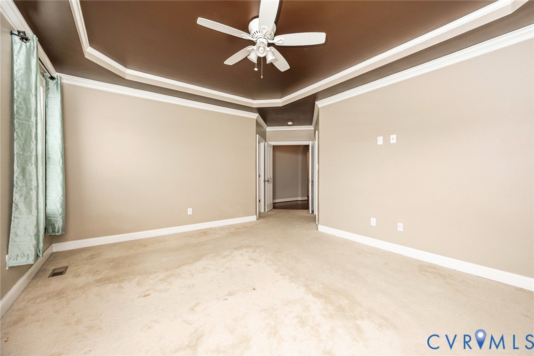 Tray ceiling with recessed architectural detailing, neutral wall tones, and a ceiling-mounted fan with integrated lighting