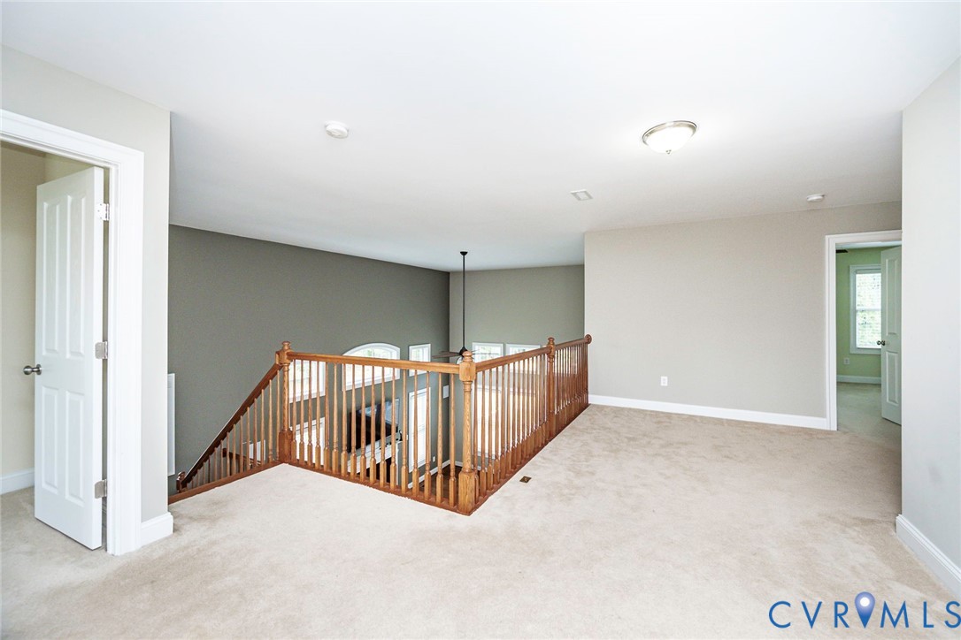 Neutral carpeted flooring, wood balustrade railing, dual-tone wall color, flush-mount lighting, and multi-panel interior doors