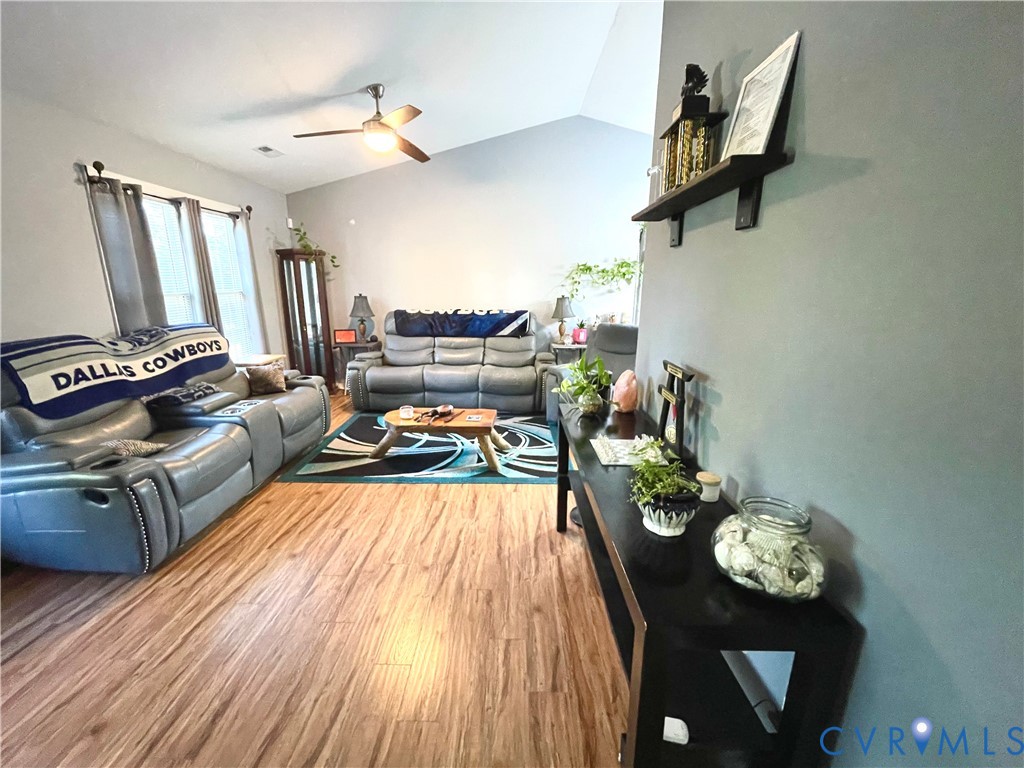 Vaulted ceilings, wood-finish flooring, and a ceiling fan with integrated lighting