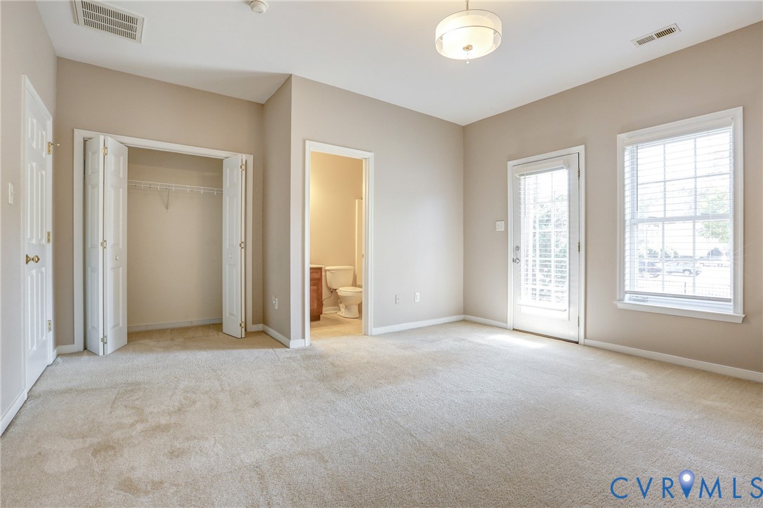 Neutral-toned interior featuring carpeted flooring, a reach-in closet with double bifold doors, a glass-panel exterior door, and natural light from a multi-pane window