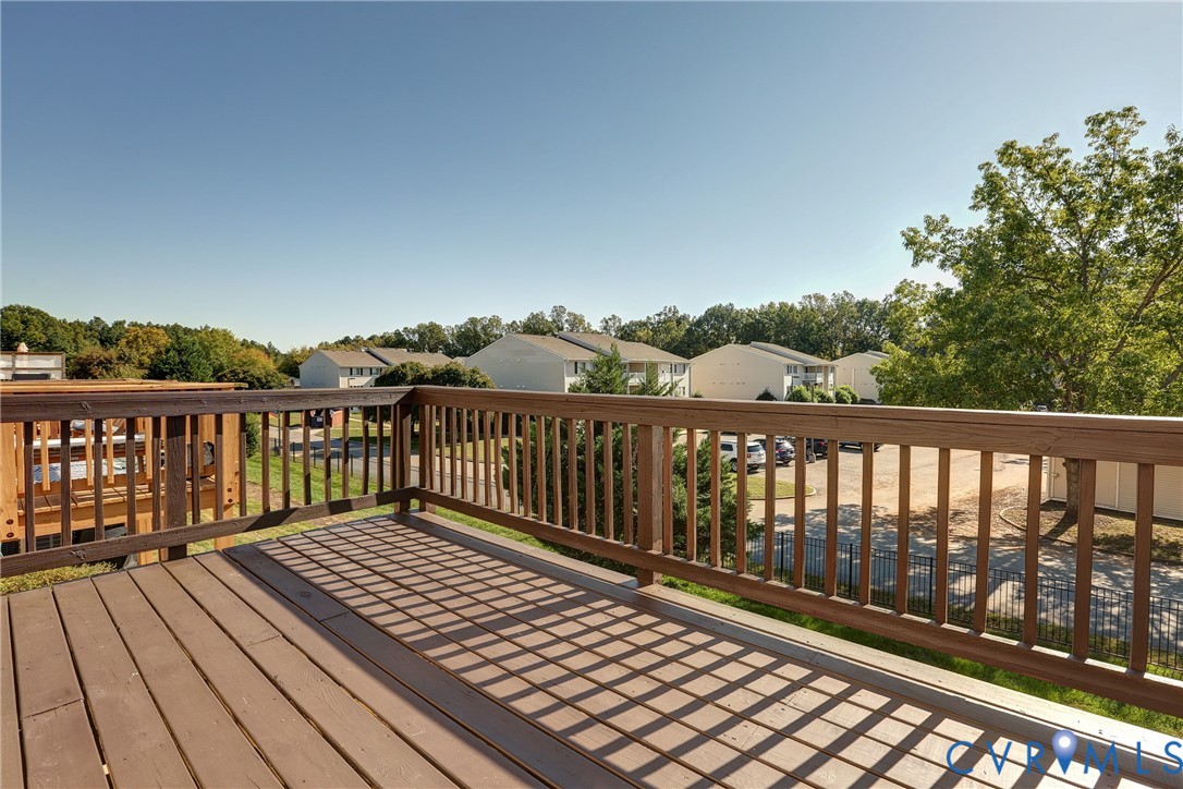 Elevated wood deck featuring vertical wood balusters and a horizontal wood railing