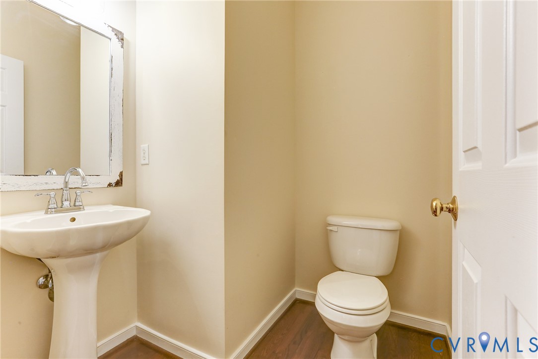 Pedestal sink with a polished chrome faucet, framed mirror, and wood-finish flooring