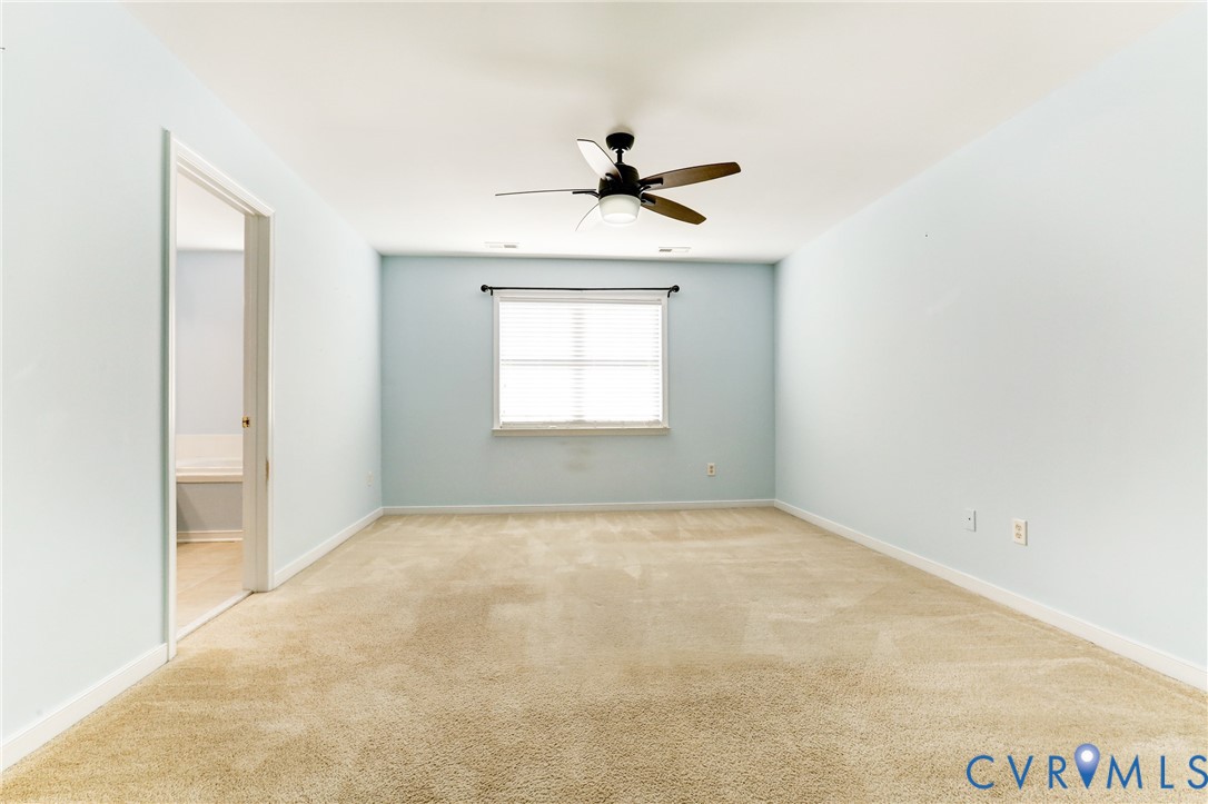 Room featuring neutral wall tones, wall-to-wall carpeting, a center-mounted ceiling fan with light fixture, and a window with a curtain rod