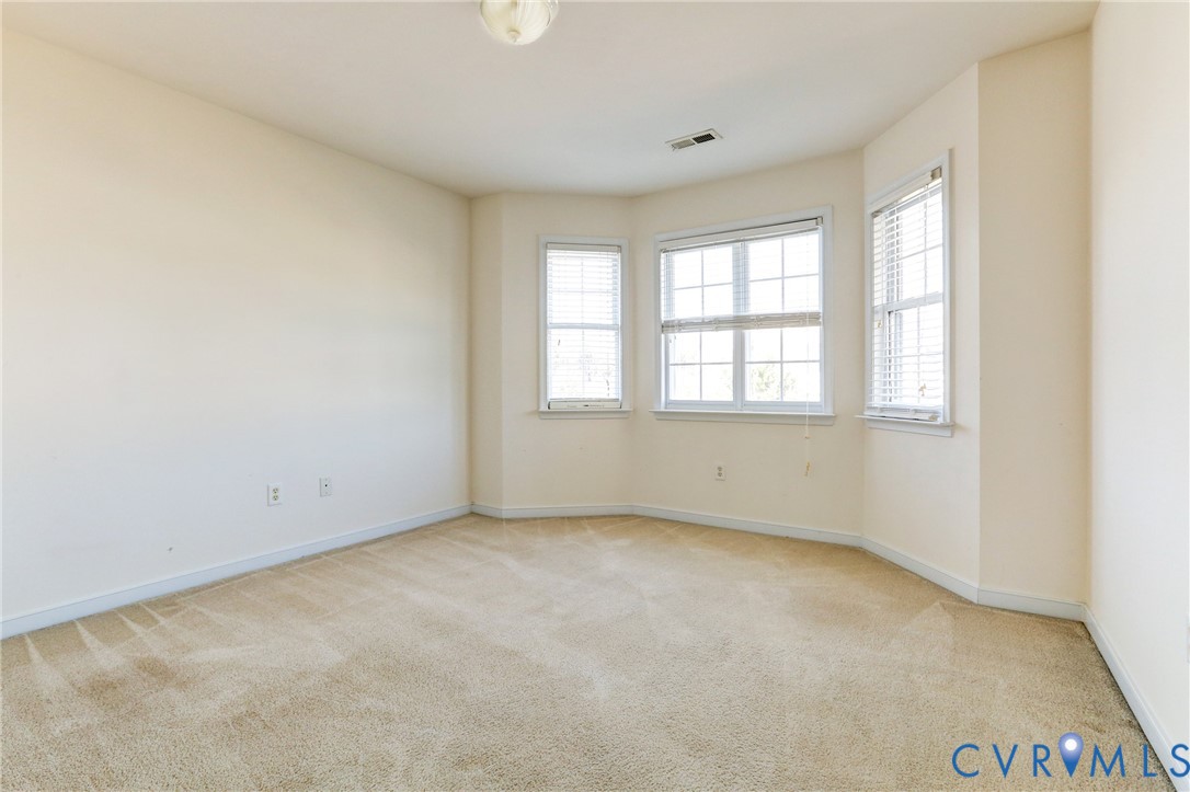 Neutral-toned room featuring a bay window, wall-to-wall carpeting, and flush-mount lighting