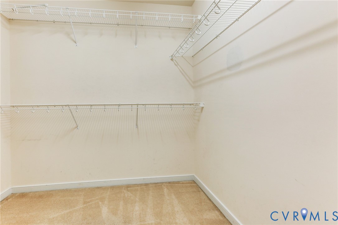 Walk-in storage space featuring dual-tier white wire shelving and wall-to-wall carpeting