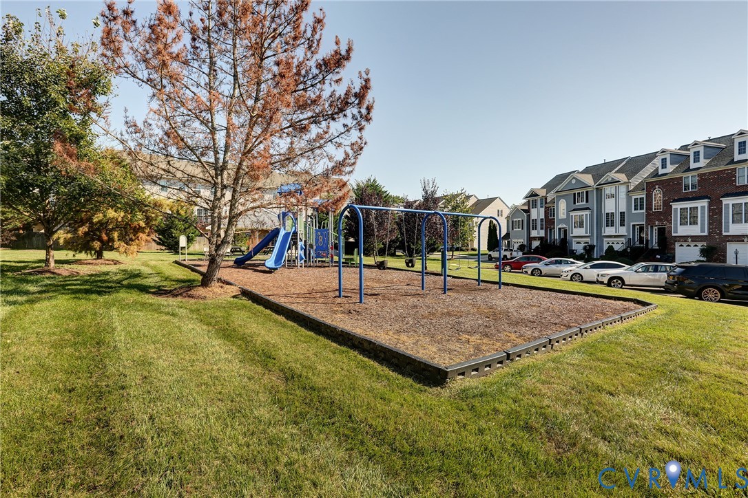 Common area featuring a playground with a slide and swings, surrounded by established landscaping and green space