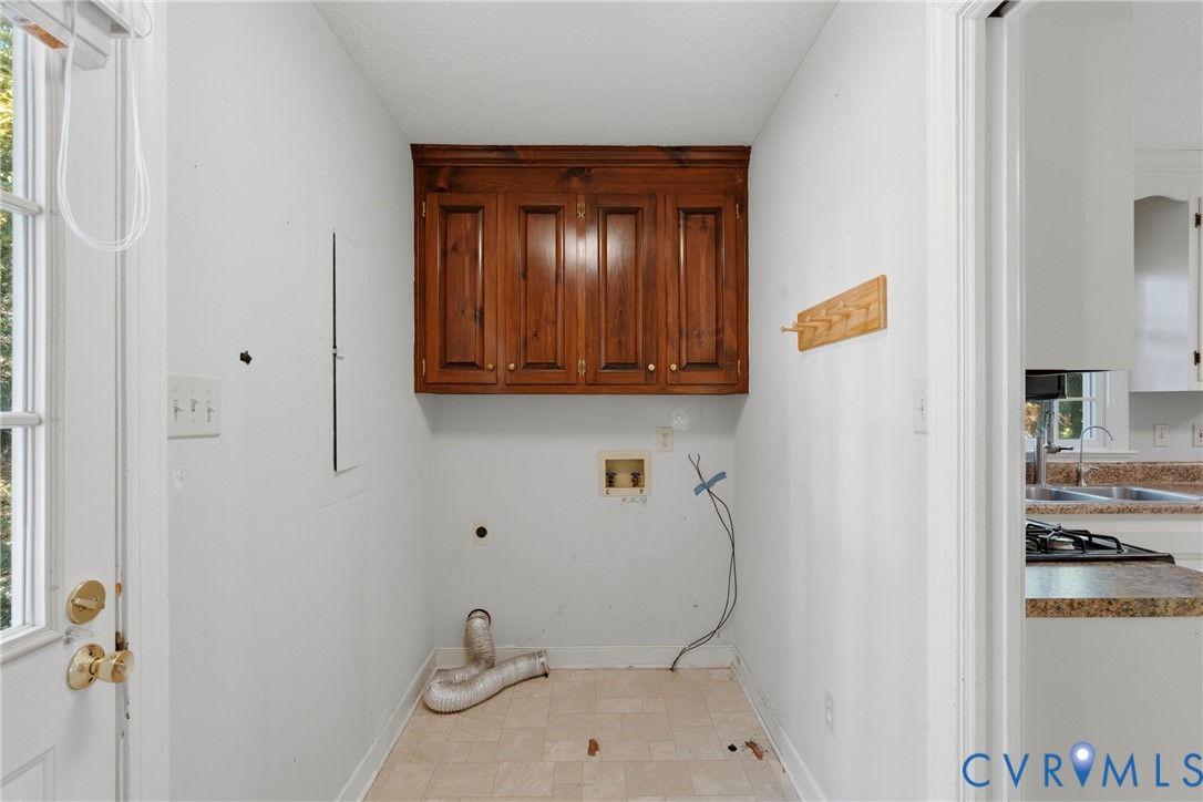 Utility space featuring wood-finish upper cabinetry, tiled flooring, and a dedicated exterior access door