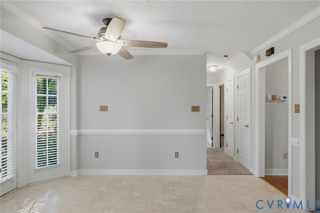 Ceramic tile flooring, crown molding, chair rail trim, ceiling fan with light fixture, and dual-pane glass entry doors