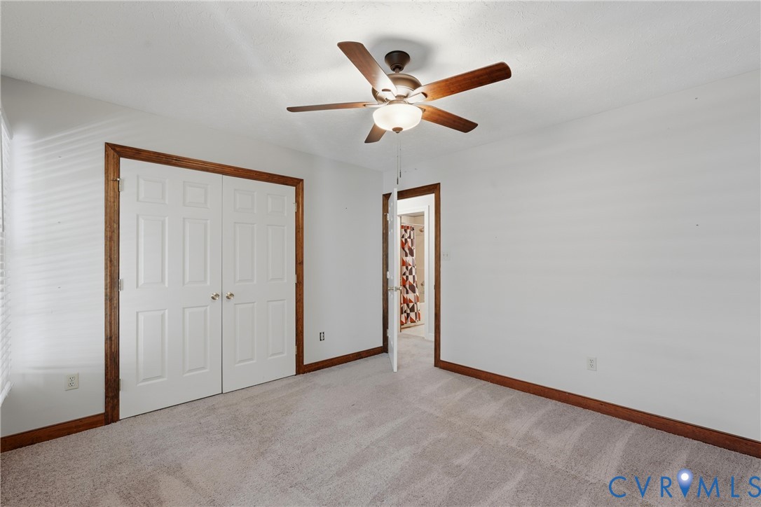 Neutral-toned carpeting, wood-trimmed door frames, double-panel closet doors, and a ceiling fan with integrated lighting