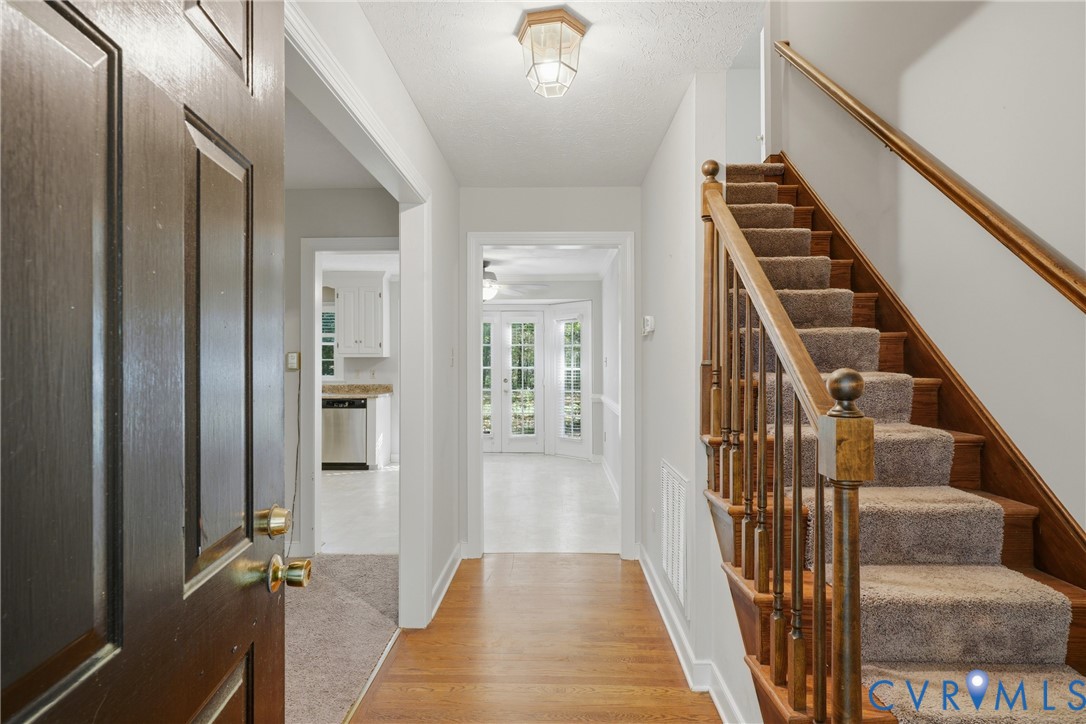 Foyer featuring wood-finish flooring, staircase with wood handrail, balusters, and carpeted treads, and overhead lantern-style ceiling light