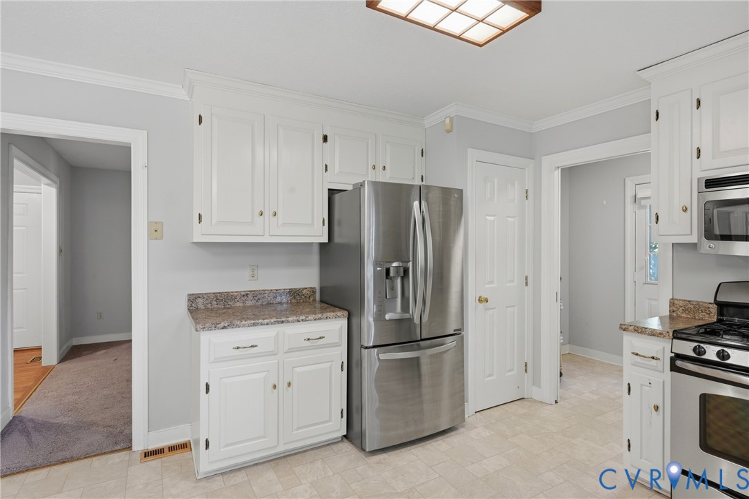 Kitchen featuring white cabinetry, stone-finish countertops, stainless steel refrigerator, built-in microwave, and tile flooring
