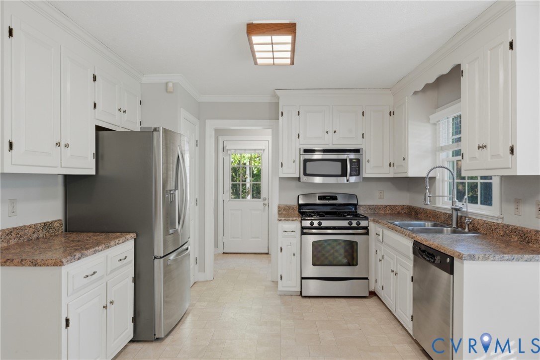 Kitchen featuring white shaker-style cabinetry, stainless steel appliances, stone-patterned countertops, a stainless steel sink with a high-arch faucet, and a flush-mount wooden frame ceiling light