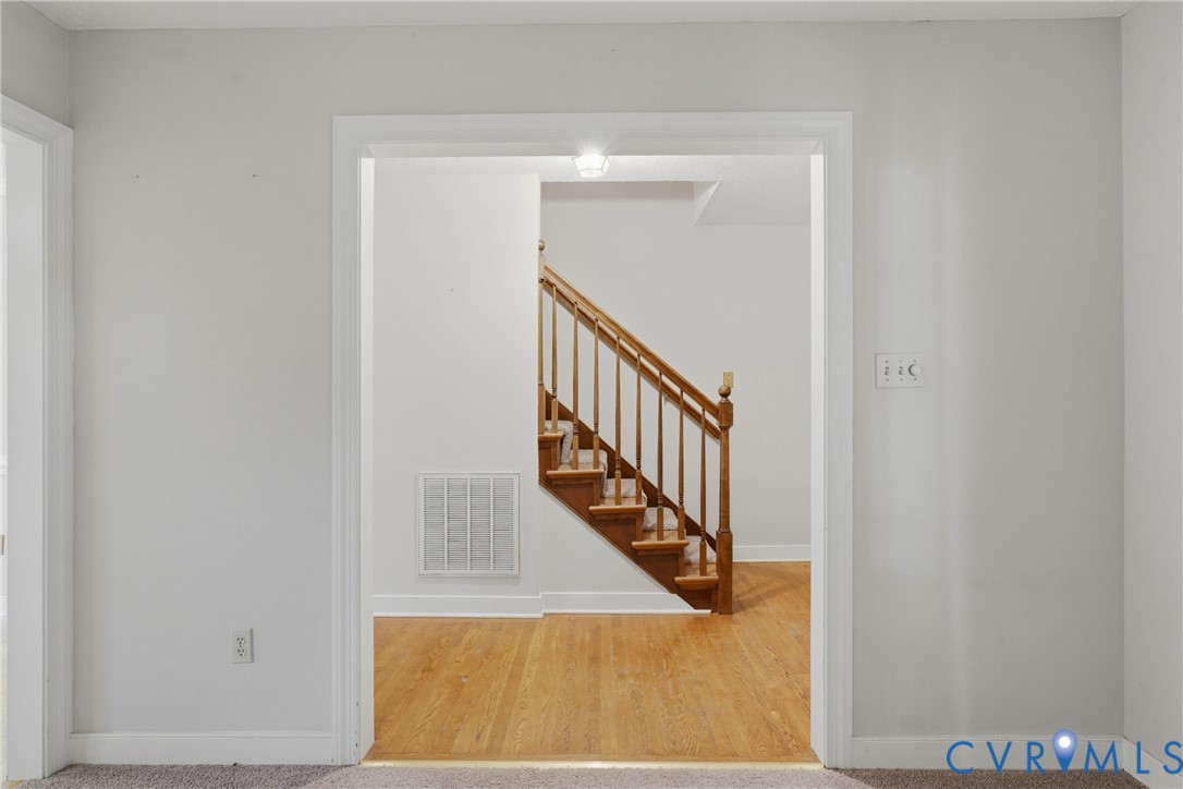 Interior doorway featuring wood-finish flooring and a staircase with a wooden balustrade
