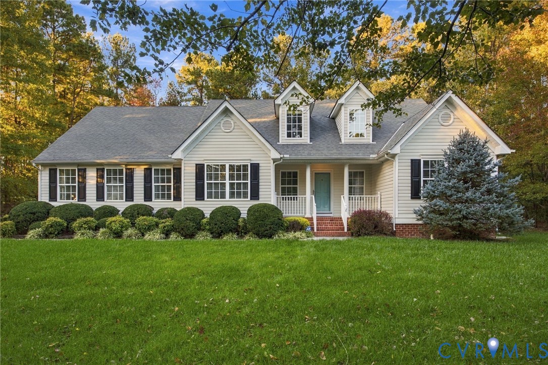 Traditional exterior featuring light-toned lap siding, multiple roof gables, dormer windows, a covered front porch, and brick foundation detailing Traditional exterior featuring light-toned lap siding, multiple roof gables, dormer windows, a covered front porch, and brick foundation detailing