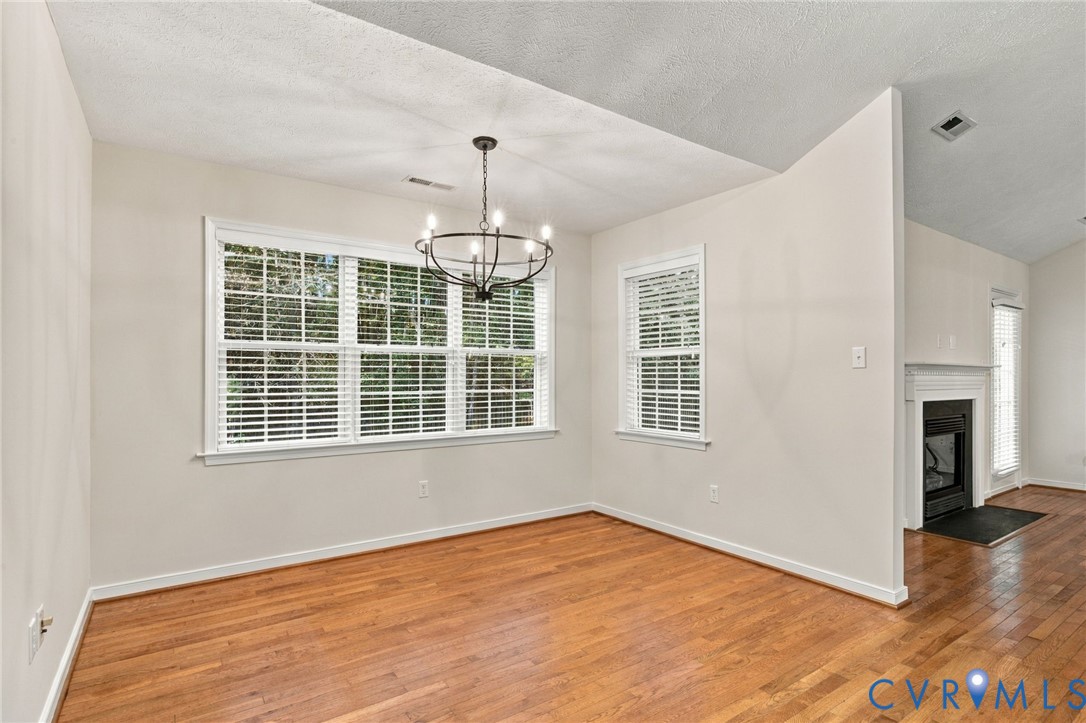 Wood-finish flooring, vaulted ceilings, multi-pane windows with integrated blinds, and a suspended multi-arm light fixture