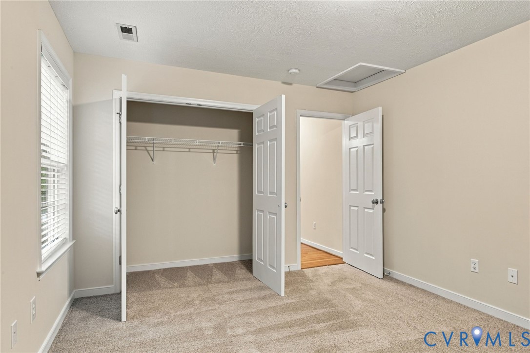 Interior space featuring neutral wall tones, wall-to-wall carpeting, a window with horizontal blinds, and a built-in closet with double doors