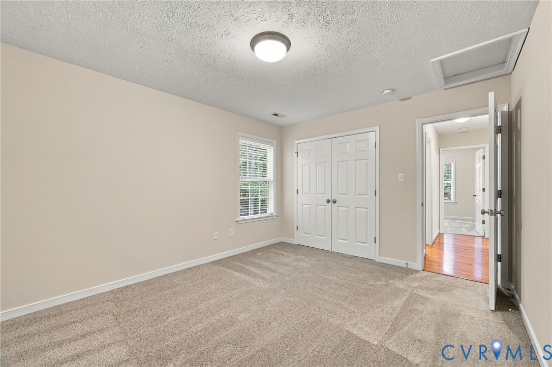 Room featuring neutral-toned carpeting, double-panel closet doors, a single window, and a ceiling-mounted light fixture