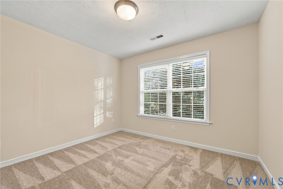 Neutral wall tones, wall-to-wall carpeting, large window with horizontal blinds, and flush-mount ceiling lighting