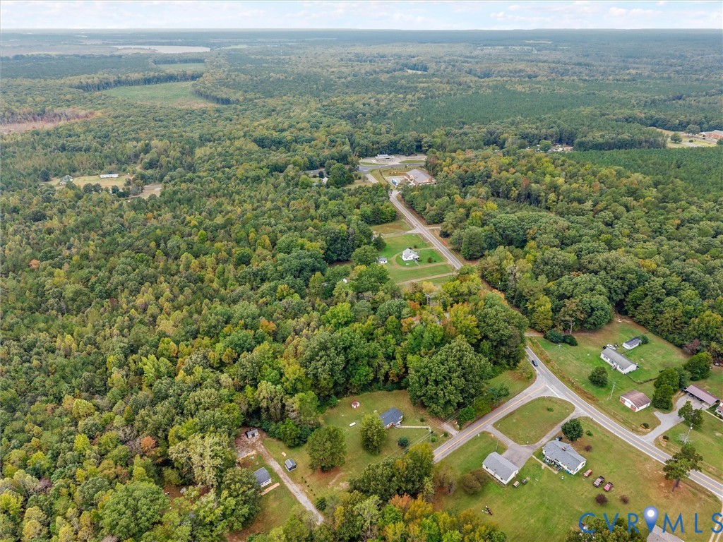 Aerial perspective of an expansive land parcel surrounded by mature woodland and established thoroughfares