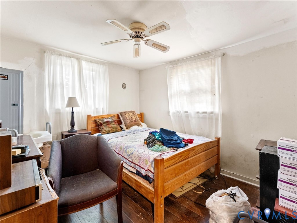 Room featuring wood-finish flooring, dual windows with natural light, and a ceiling-mounted fan with integrated lighting