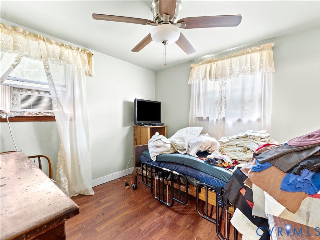 Interior room featuring wood-finish flooring, a ceiling fan with integrated lighting, and dual windows