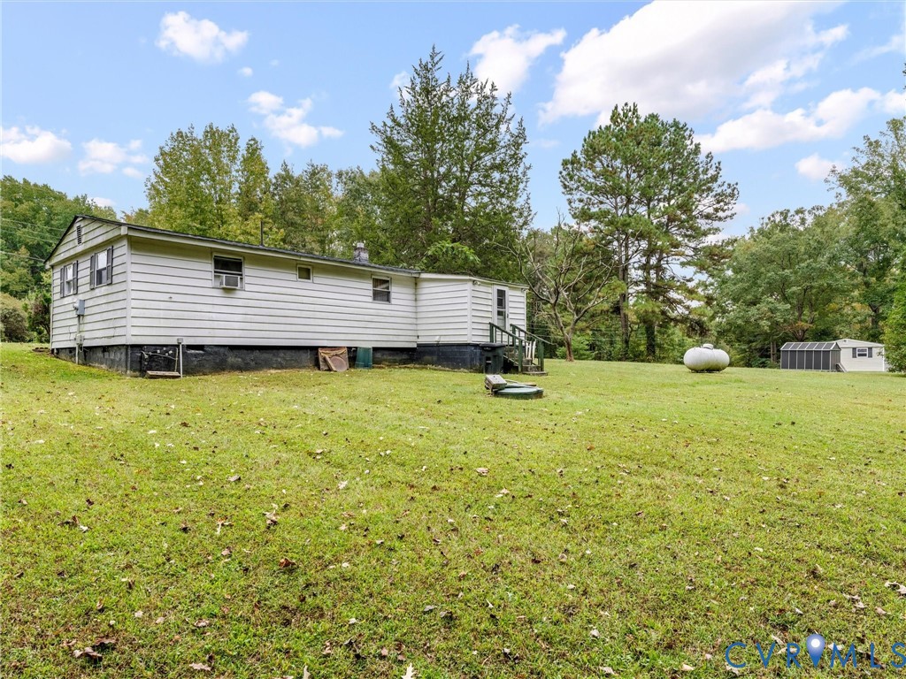 Siding exterior with a grass lawn, mature trees, and a detached structure