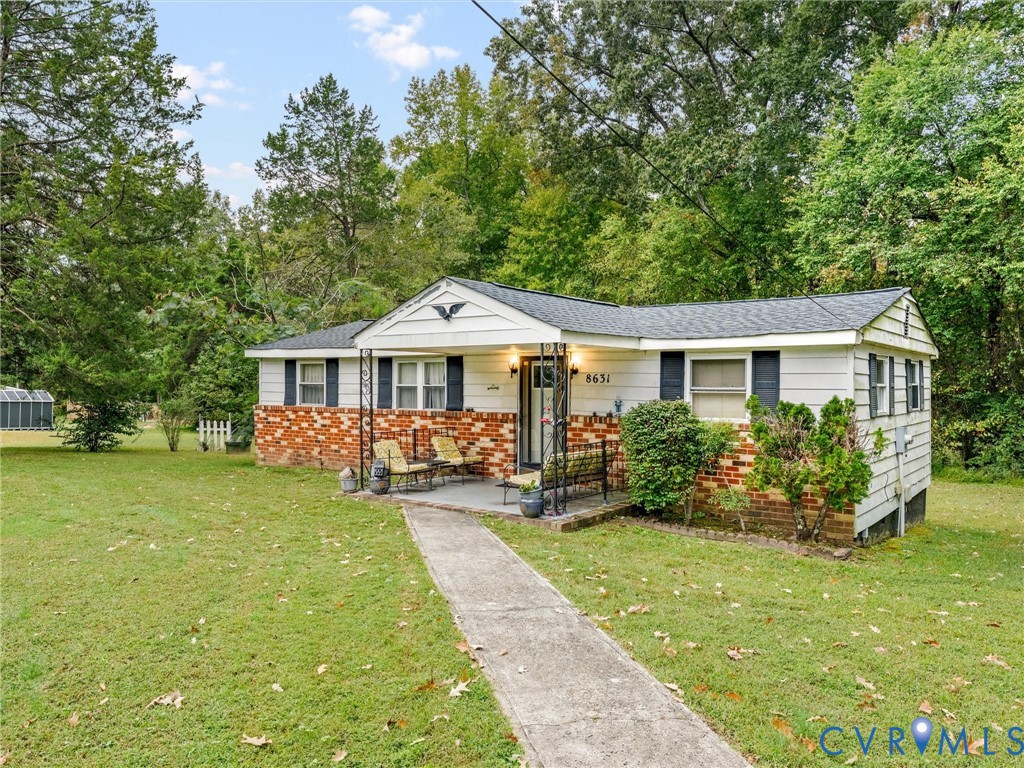 Ranch-style exterior featuring horizontal lap siding, a partial brick facade, a covered front porch with decorative iron columns, and a concrete walkway